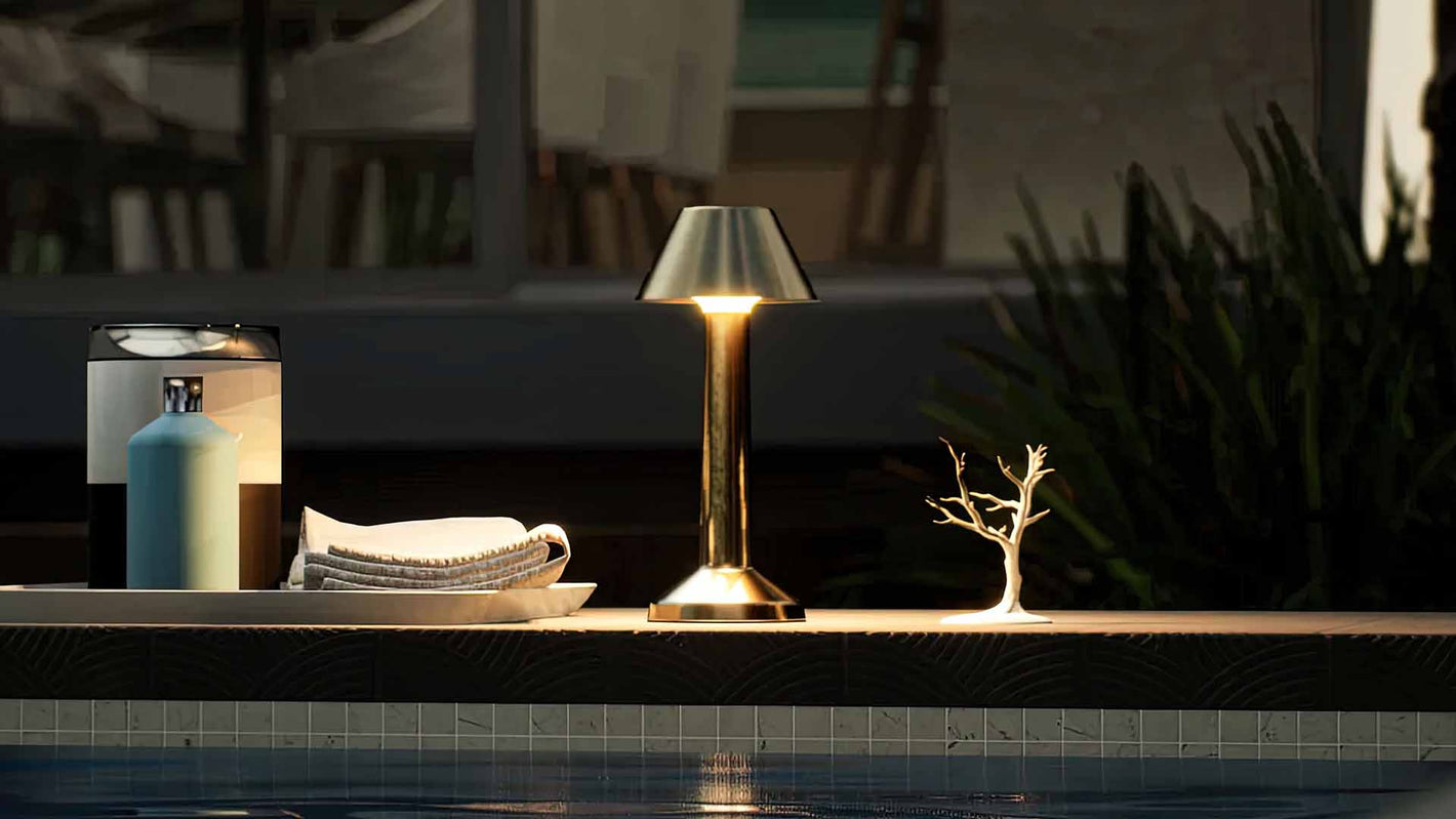 Bella | Cordless Table Lamp | Iron, Acrylic | Gold color of product | Warm light on | Mid-range distance to lamp | Near outdoor pool | Evening