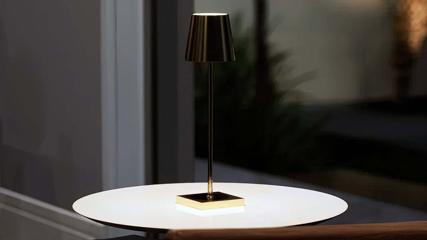 Olivia | Cordless Table Lamp | Aluminum | Gold color of product | Warm light on | Mid-range distance to lamp | At coffee table | Modern interior | Evening | Scene 2