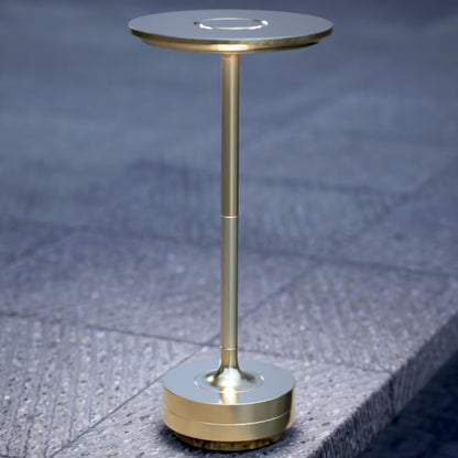 Amberly | Cordless Table Lamp | Aluminum | Gold color of product | White light on | Close-up distance to lamp | Near outdoor pool | Evening | Scene 4