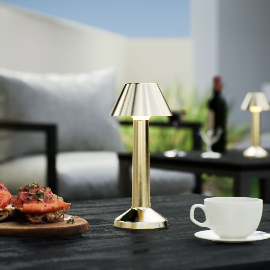 Bella | Cordless Table Lamp | Iron, Acrylic | Gold color of product | Warm light on | Close-up distance to lamp | At backyard patio | Noon