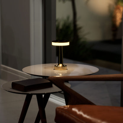 Halo Slim | Cordless Table Lamp | Iron, Acrylic | Gold color of product | Warm light on | Mid-range distance to lamp | At coffee table | Modern interior | Evening  | Scene 2